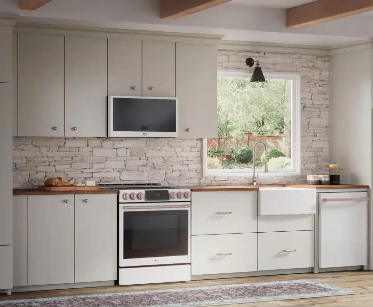 A modern kitchen with gray shaker cabinets, a white subway tile backsplash, wood countertops, and a farmhouse sink beneath a window.