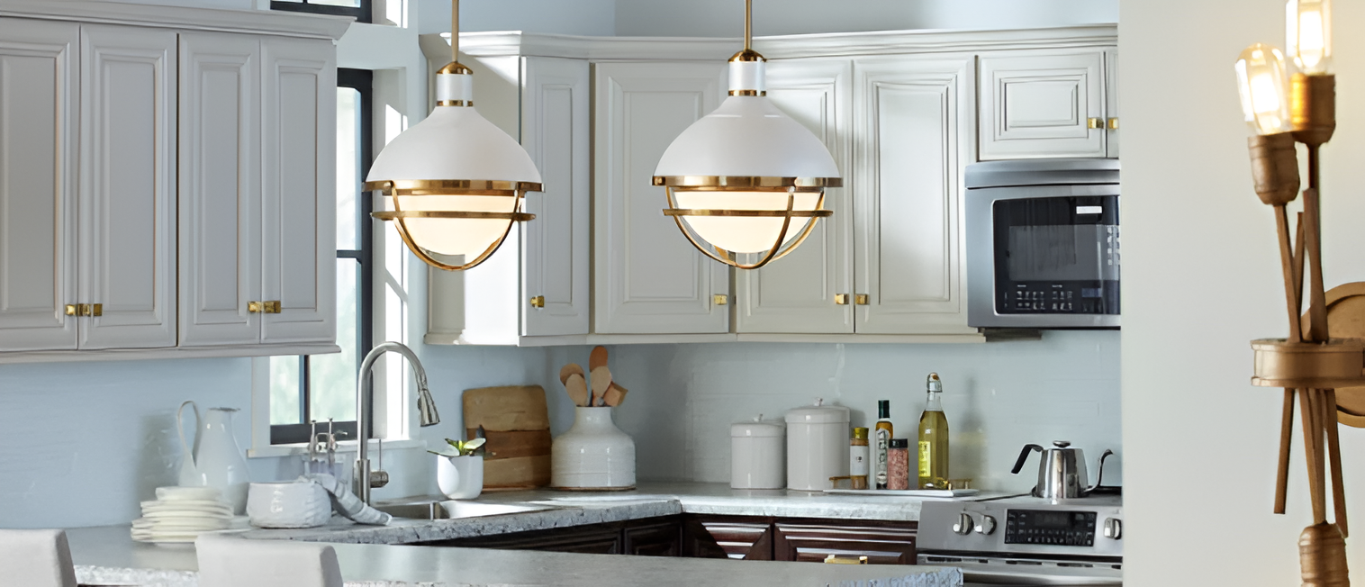 Bright kitchen with white cabinets, brass pendant lights, marble countertops, and modern stainless steel appliances.