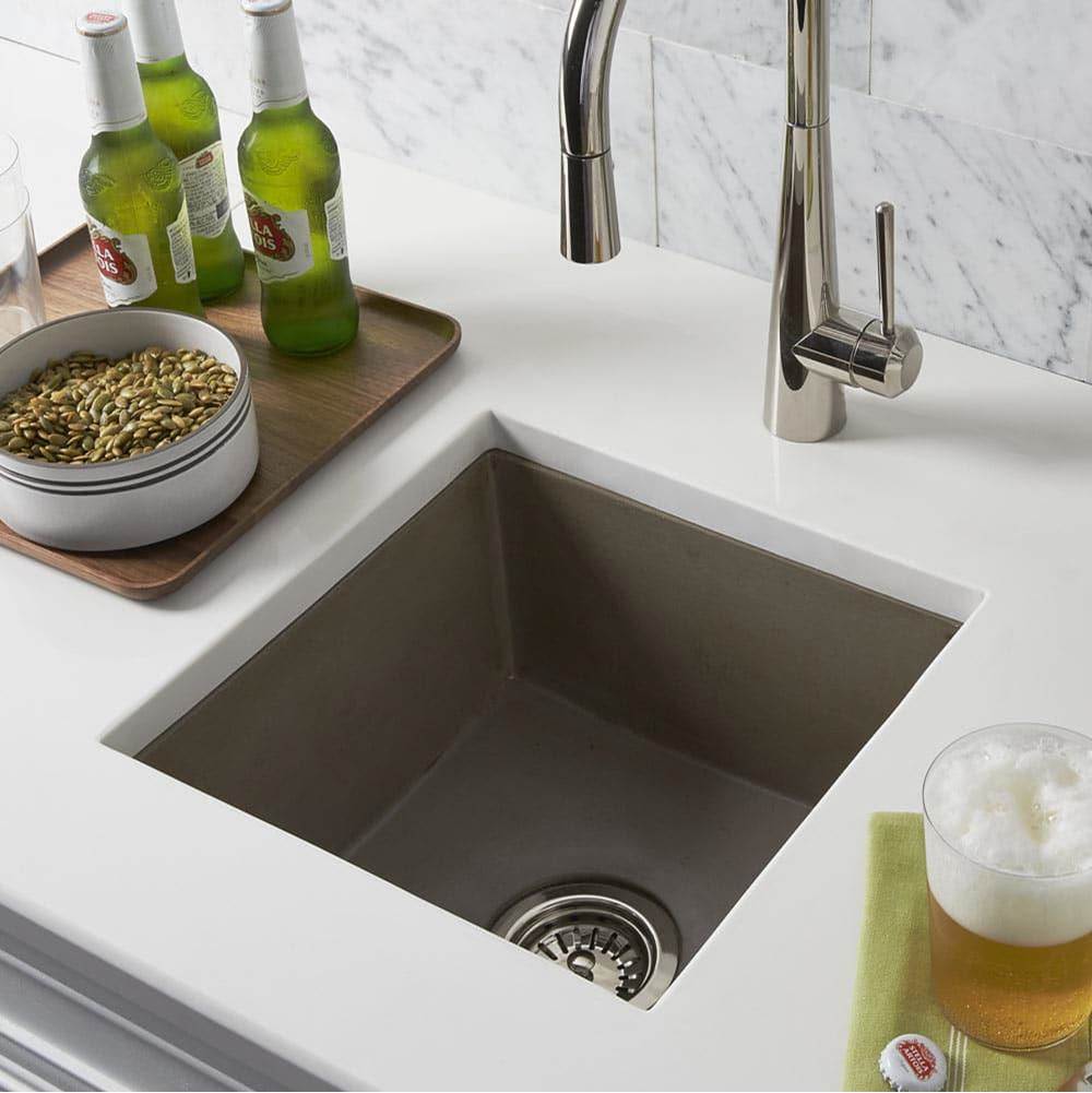 Bath and Bronze concrete bar prep sink set in a white countertop with a modern pull-down faucet.