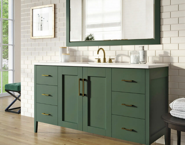 Green bathroom vanity with brass faucet, matching hardware, framed mirror, and white subway tile.