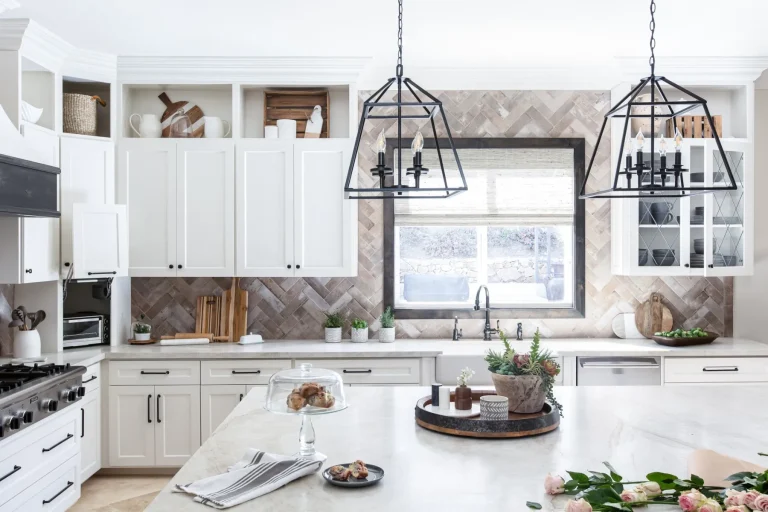 Modern white kitchen with black pendant lights above a marble island, open shelving, and a subway tile backsplash.