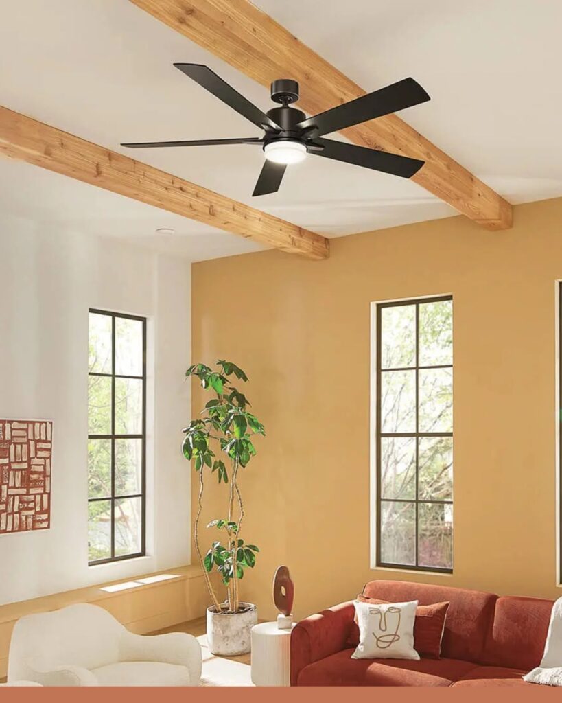Matte black ceiling fan with LED light in a living room with wood beams and warm decor.