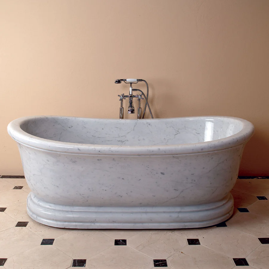 Freestanding white stone soaking tub with floor mounted faucet creating a luxurious spa style bathroom centerpiece.